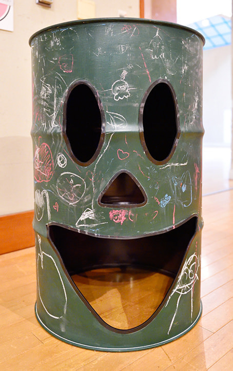 黒板塗装されたドラムカンに子供がお絵かき