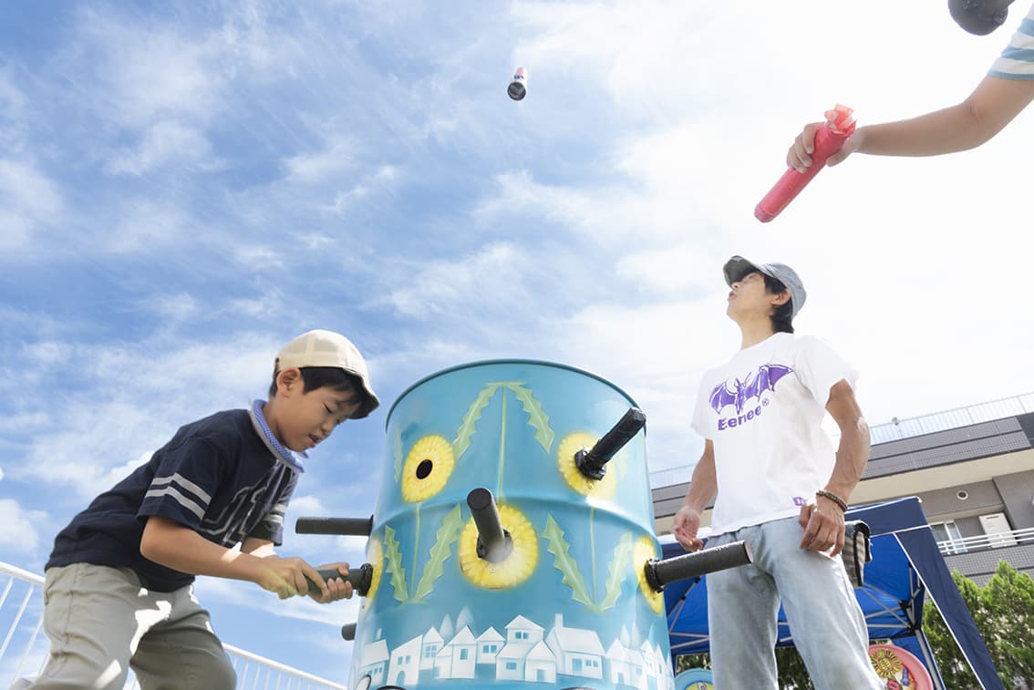 カラフルなドラム缶に棒を突っ込む少年