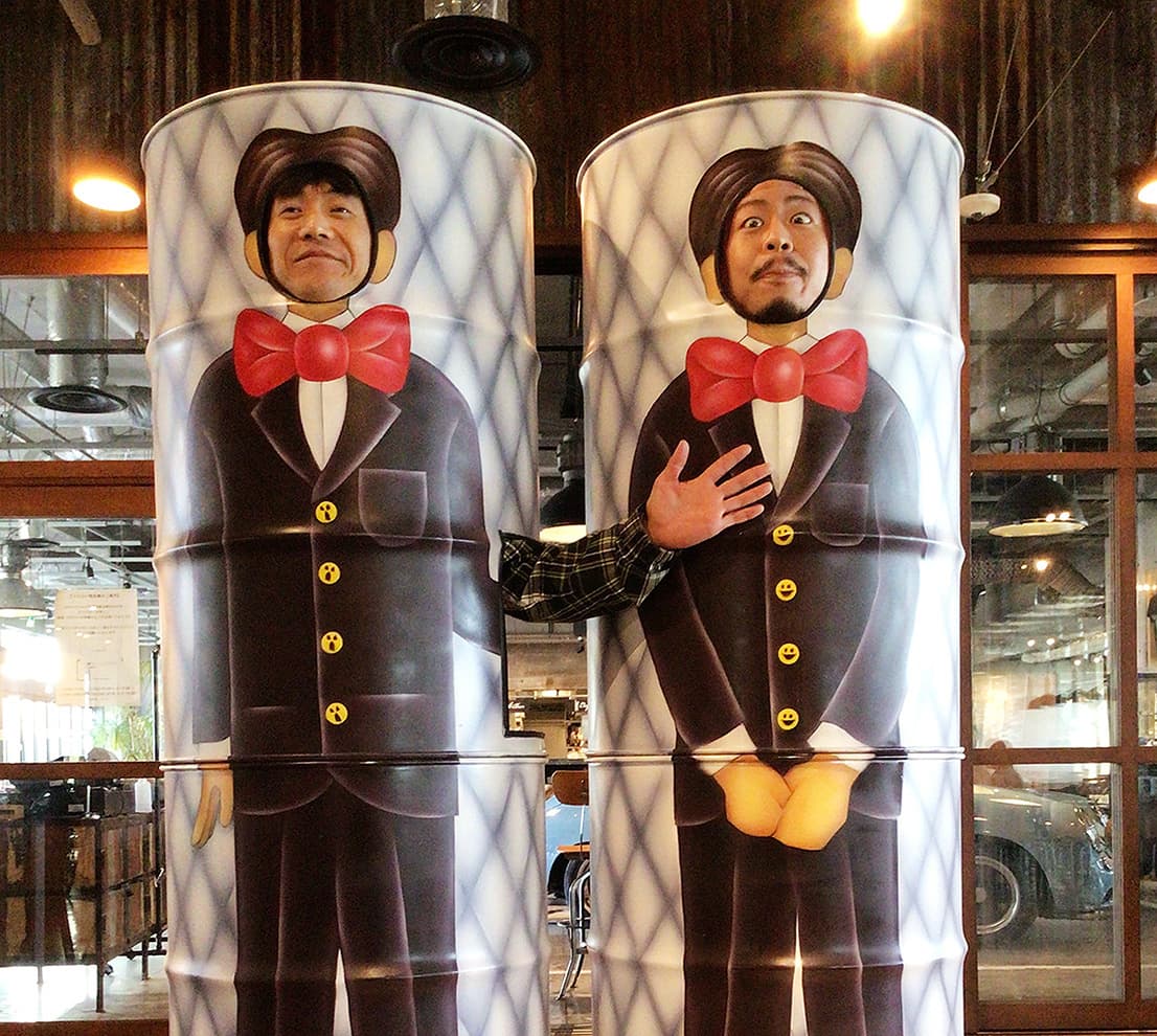 顔がはめられるドラム缶